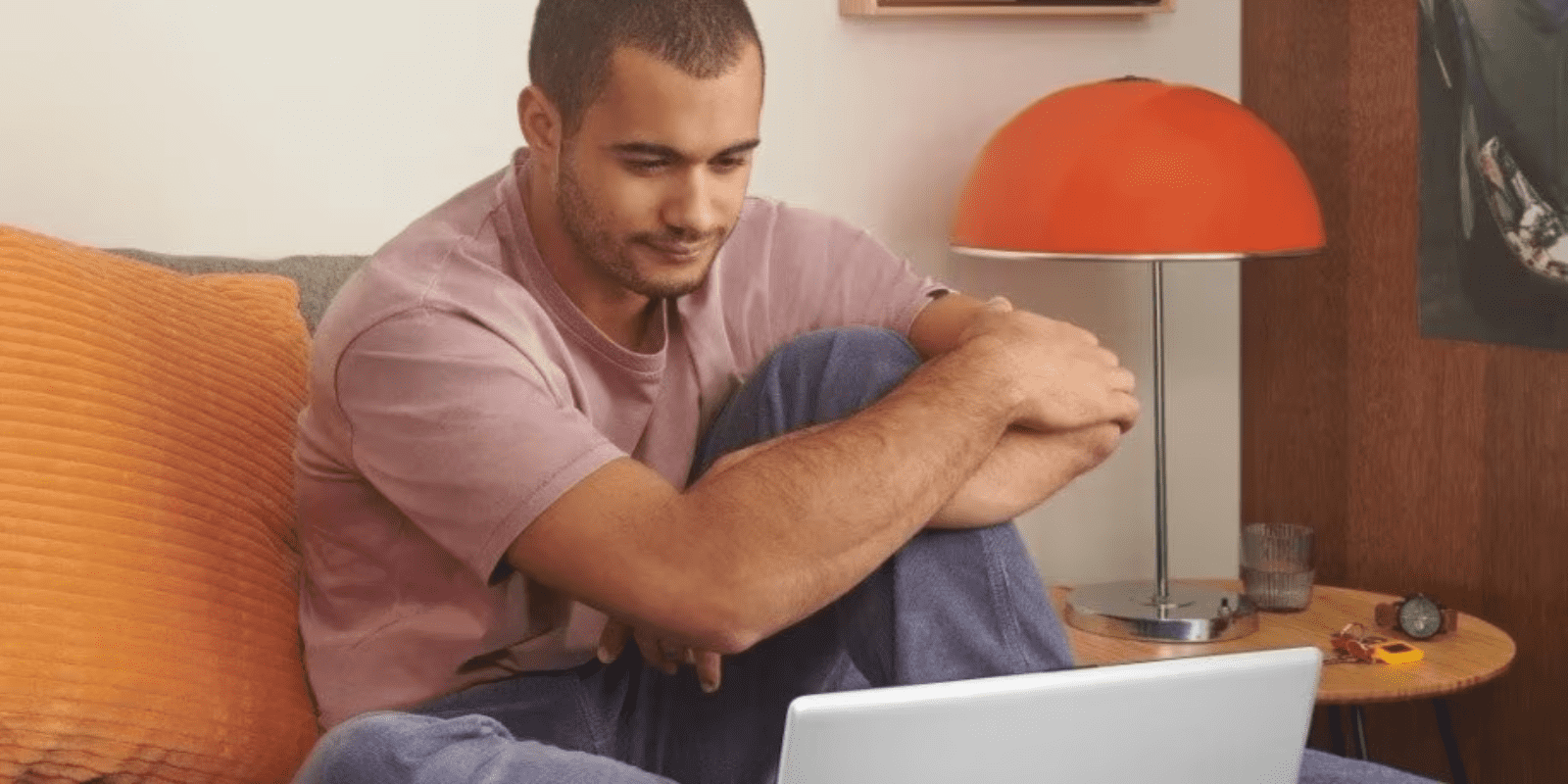 Man focusing on laptop while working from home on orange couch